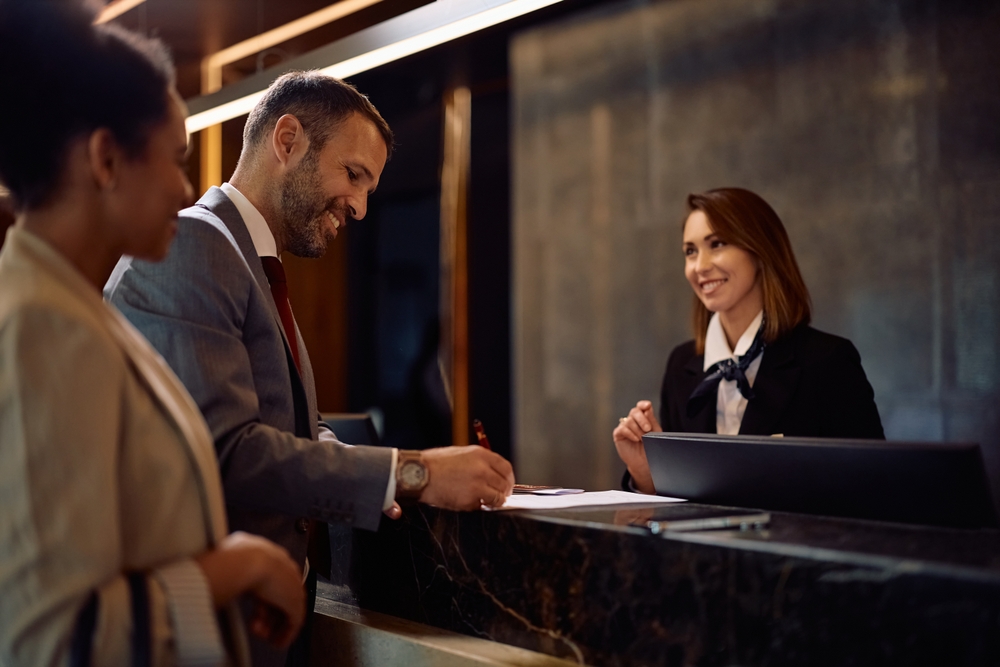 Business,Colleagues,Checking,In,At,Hotel,Reception,Desk.,Focus,Is